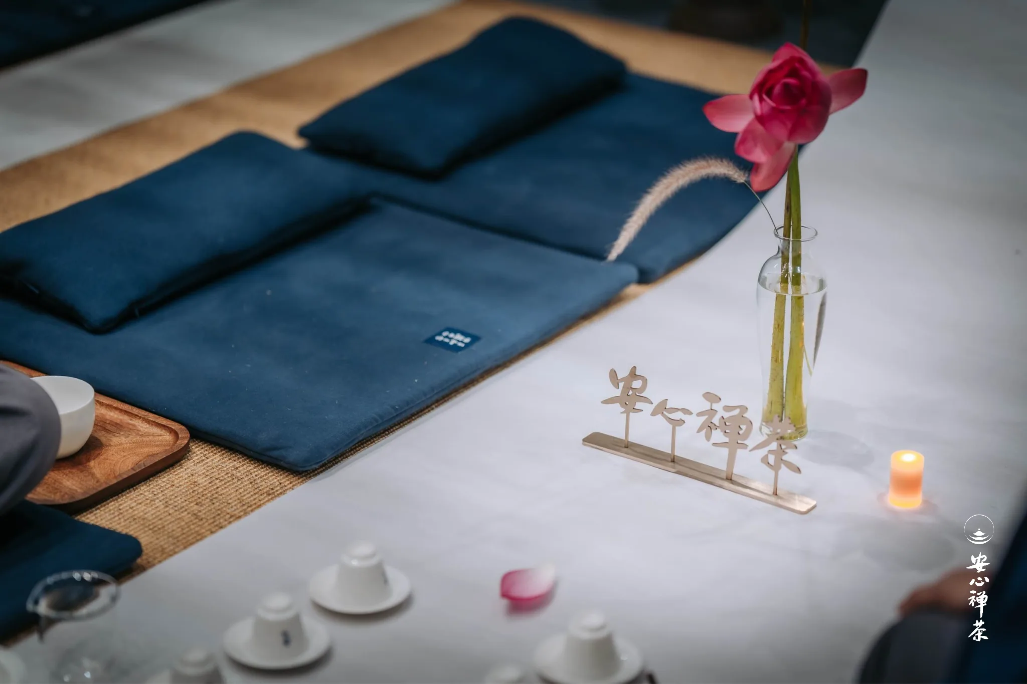 瑜伽垫、瑜伽砖、粉红花朵、木制禅意装饰和蜡烛组成的冥想空间